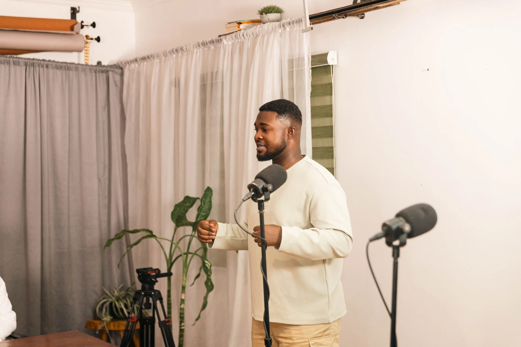 A coach demonstrating a speaking technique beside microphones